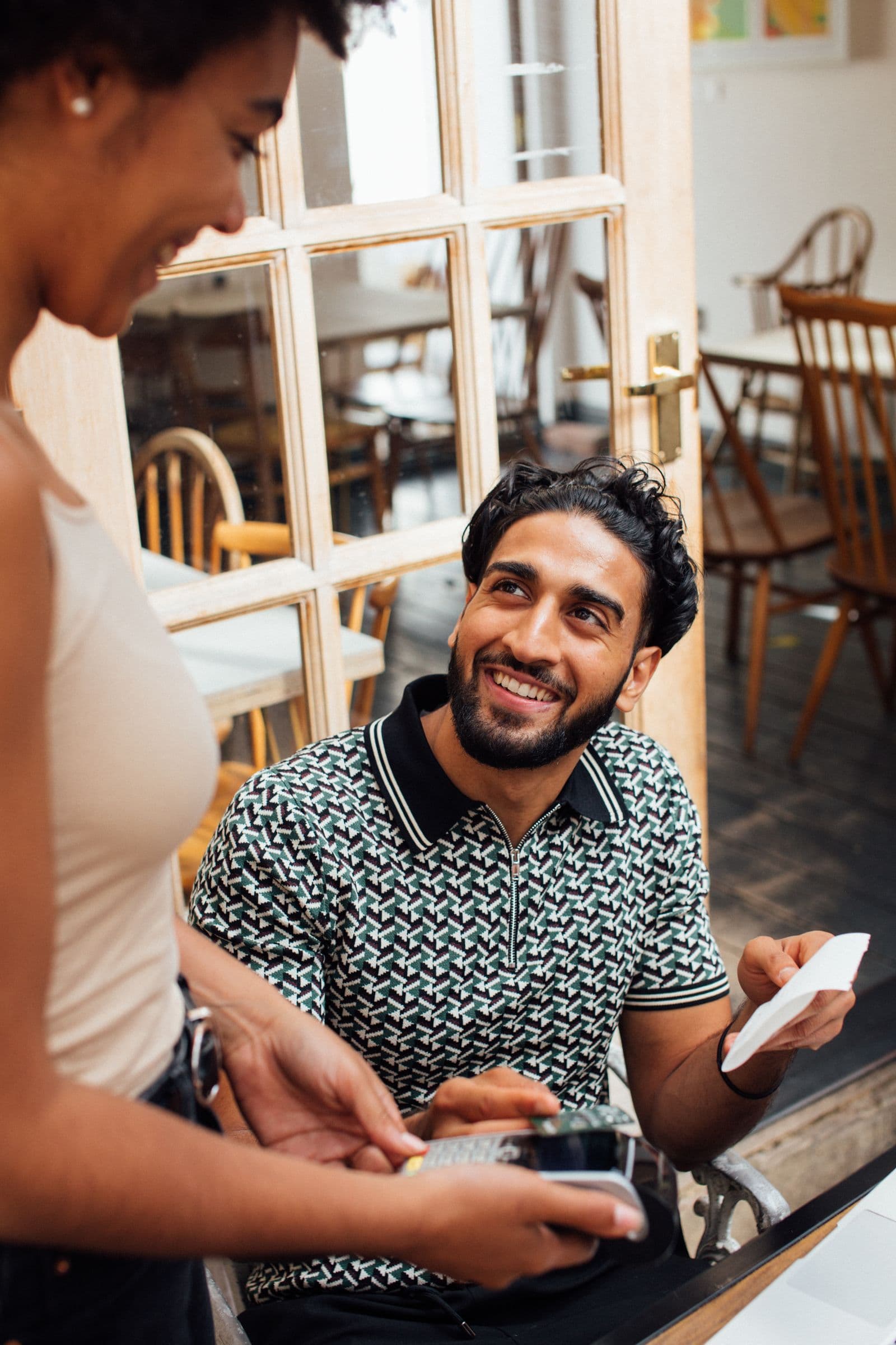 A customer paying by card machine at a cafe table